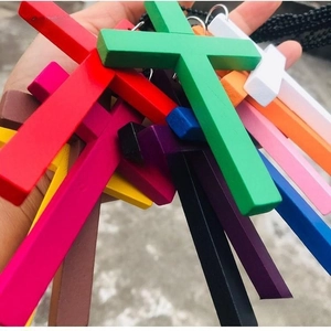 Close-up of colorful wooden cross pendants in various vibrant shades held in hand