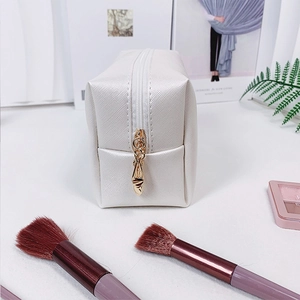 White textured PU leather makeup bag with gold zipper and stylish makeup accessories