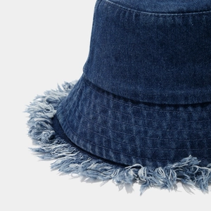 Detailed close-up of frayed edges and twill texture on dark blue denim bucket hat