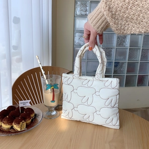 Quilted rabbit pattern handbag detail featuring soft white fabric and stylish handles