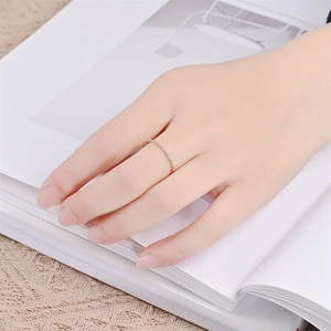 Detail of rose gold twisted rope ring worn by model on a minimalist background