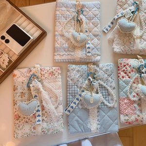 Flat lay of quilted floral storage pouches with pearl chains and heart pendants on desk