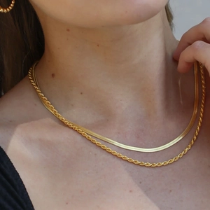 Detail of layered gold double chain featuring a rope link and flat snake necklace style