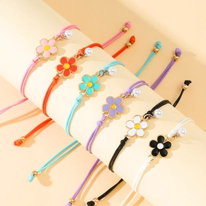 Detail of six handmade woven flower bracelets with pearls on a cylindrical display