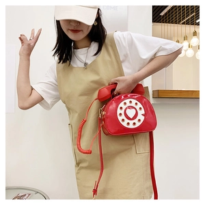 Detail of red patent leather crossbody bag featuring a vintage telephone dial design