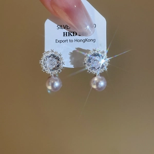 Detail of flower shaped stud earrings with large central crystal and purple pearl drop