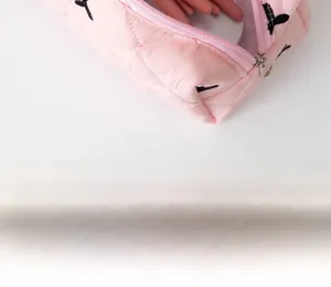 Dettaglio del beauty case rosa trapuntato con cerniera e pennello per il trucco