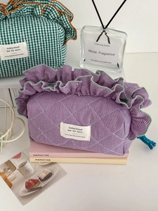 Quilted checkered cosmetic bag with ruffle trim and drawstring in purple and green cotton