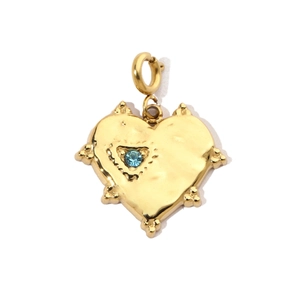 Close-up of golden heart pendant with blue zircon stone and textured hammer-finish detail