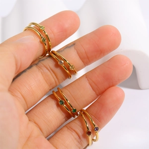 Detail of stacked gold titanium rings with colorful round December birthstones on fingers