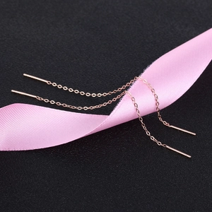 Detail of rose gold S925 silver long chain earrings displayed on elegant pink silk ribbon