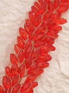 Detailed view of red faceted crystal beads woven with gold wire on a bridal headpiece