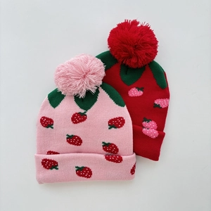 Detail of pink and red jacquard strawberry knit hats with fluffy pom-poms for girls