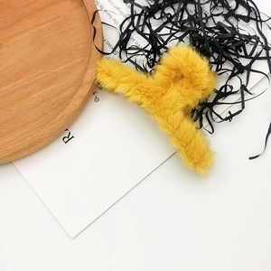 Detailed view of a fuzzy yellow plush hair claw clip on a rustic wooden tray decoration