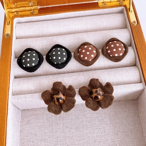 Detail view of rhombic fabric stud earrings with polka dot and leopard print patterns