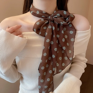 Close-up of elegant dark brown silk scarf with blue polka dots tied in a chic bow