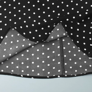 Detail of polka dot dress fabric showing high-quality stitching and hem on black fabric
