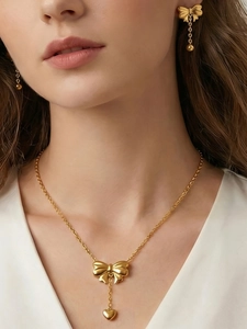 Close-up of golden bow-knot jewelry set including necklace and earrings on a model