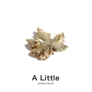 Close-up of golden maple leaf brooch showing intricate metal texture and back pin detail