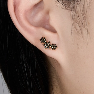 Close-up of elegant black floral earrings with gold plating on model's ear