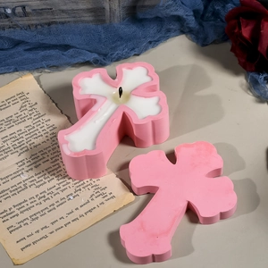 Rosafarbene Kreuzkerze auf gotischem Hintergrund mit Rosen und Vintage-Buch