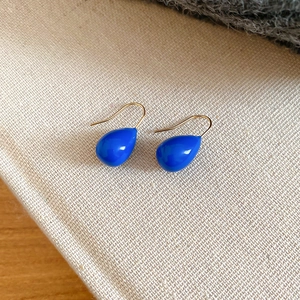 Gros plan détaillé de boucles d'oreilles goutte bleues avec crochets dorés sur tissu