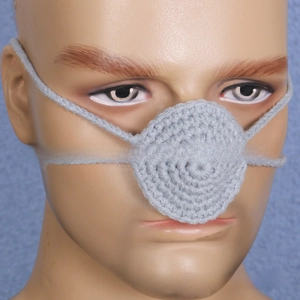 Close-up of a handmade crochet nose warmer in light grey yarn with elastic head straps
