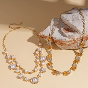 Boheemse goudkleurige ketting met parels en zirkoon kristallen op natuursteen achtergrond