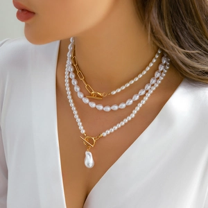 Close-up of layered baroque pearl necklace with gold paperclip chain and T-bar clasp