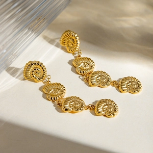 Close-up of elegant gold-plated shell earrings on a textured surface with soft lighting