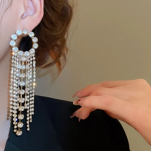 Detailed close-up of sparkling long tassel earrings with rhinestones on model