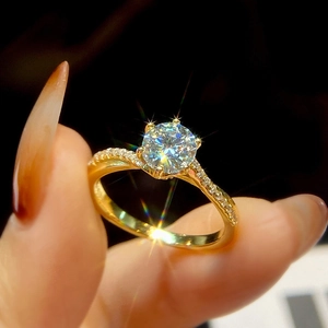 Close-up of a gold engagement ring featuring a large round diamond and micro-pave band