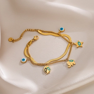 Double-layered gold elephant and evil eye charm bracelet on elegant white satin