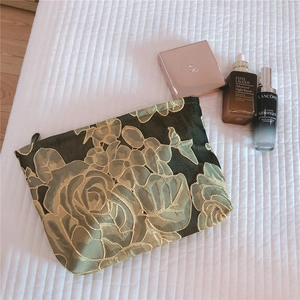 Detail of vintage jacquard floral makeup bag with golden roses on dark green fabric