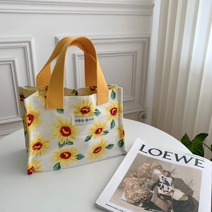 Close-up of portable sunflower canvas lunch bag with yellow handles and woven label