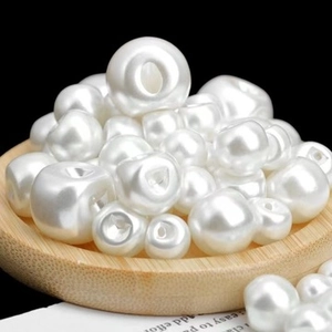 Detailed macro view of white textured faux pearls on a wooden tray for DIY jewelry