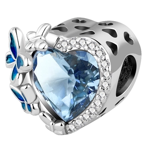 Macro view of heart-shaped blue gemstone charm with enamel butterfly and silver details