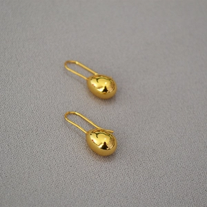 Detailed macro shot of gold teardrop earrings with a mirror-polished metallic finish