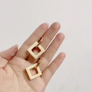 Detail shot of vintage 18k gold plated geometric hoop with white resin square charm