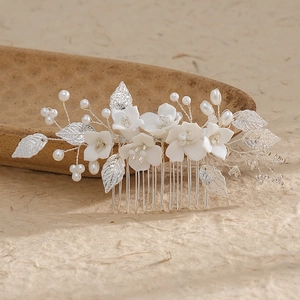 Exquisite bridal hair comb with ceramic flowers and pearls on textured paper backdrop