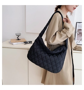 Quilted black cloud bag shown on shoulder in a stylish minimalist interior setting