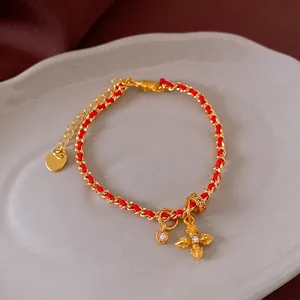 Gold plated bracelet featuring zircon heart and cross pendants with red silk thread accents