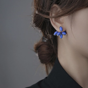 Detail showing elegant deep blue leaf-shaped stud earrings with golden metallic edges