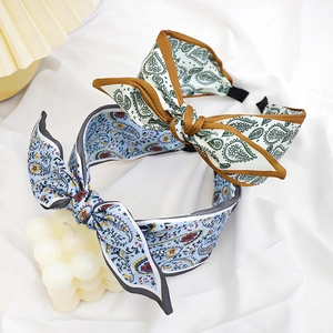 Detail view of blue and beige paisley bow headbands on a textured fabric background