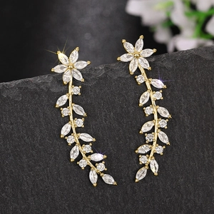 Macro shot of gold floral drop earrings featuring marquise-cut crystals on dark stone