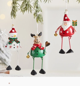 Detail of hanging metal Christmas ornaments with snowman and reindeer on pine branches