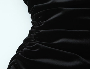Vue détaillée montrant la texture froncée et le velours noir doux de la robe