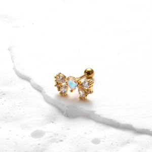 Detailed view of golden butterfly earring with heart-shaped stone and crystal inlay