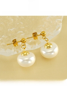 Detail showing gold plated titanium steel pearl earrings on a frosted glass tray