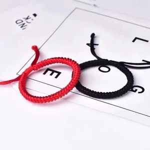 Detailed view of handmade braided red and black cord bracelets on a minimalist card